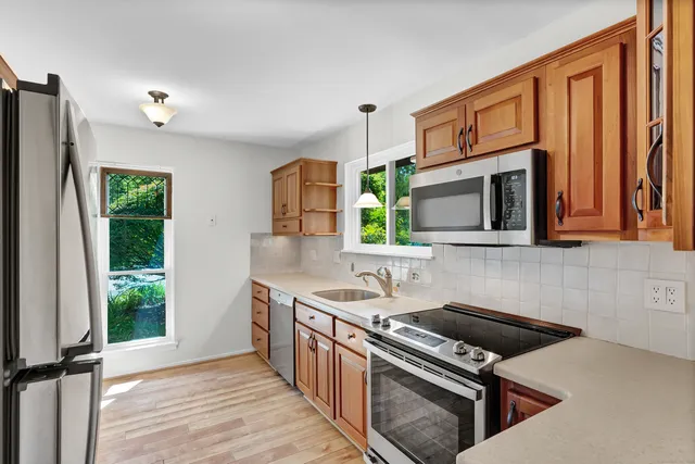 a kitchen with stainless steel appliances granite countertop a stove a sink and a microwave