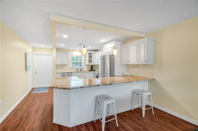 a kitchen with kitchen island granite countertop wooden floors and white cabinets