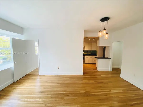 a view of kitchen and empty room with wooden floor