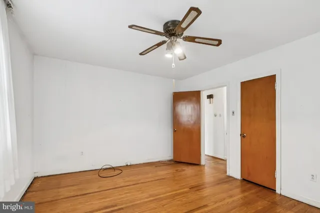 an empty room with wooden floor and ceiling fan