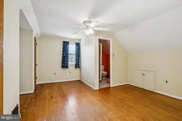 an empty room with wooden floor chandelier fan and windows