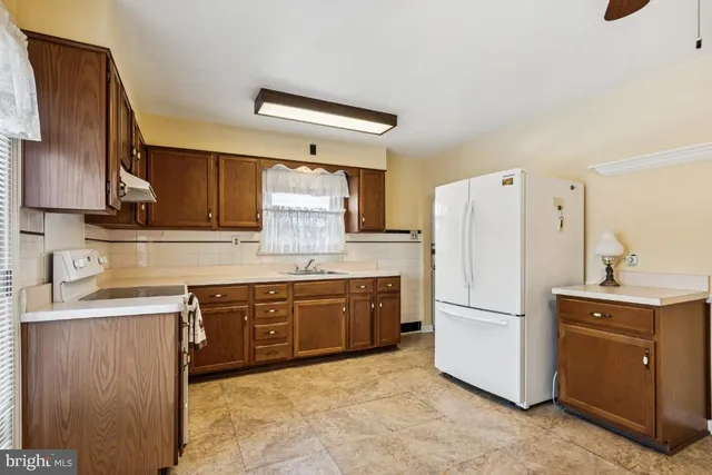 a kitchen with a refrigerator sink and wooden cabinets