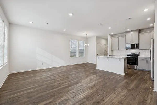 a view of kitchen with refrigerator and white cabinets