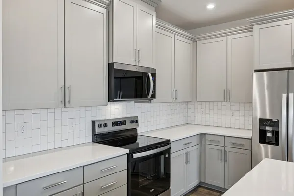 a kitchen with stainless steel appliances granite countertop a refrigerator a stove and a sink with wooden floor