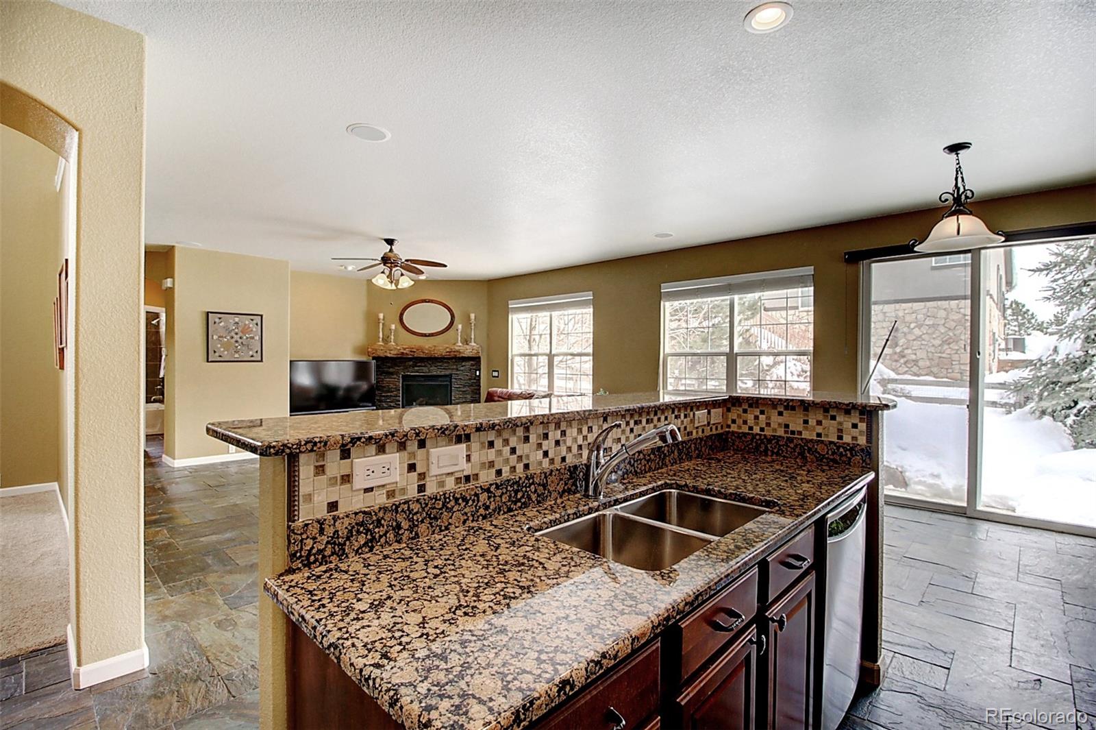 16330 Avalanche Run Broomfield, CO 80023 - Photo 9 of 39 a kitchen island with granite countertop a stove a sink a dining table and chairs
