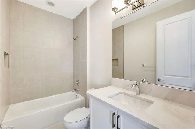 a bathroom with a granite countertop bathtub shower sink vanity mirror and toilet