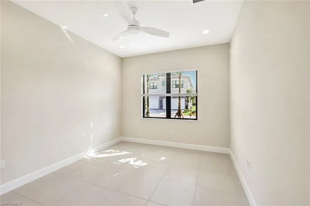 an empty room with windows and ceiling fan