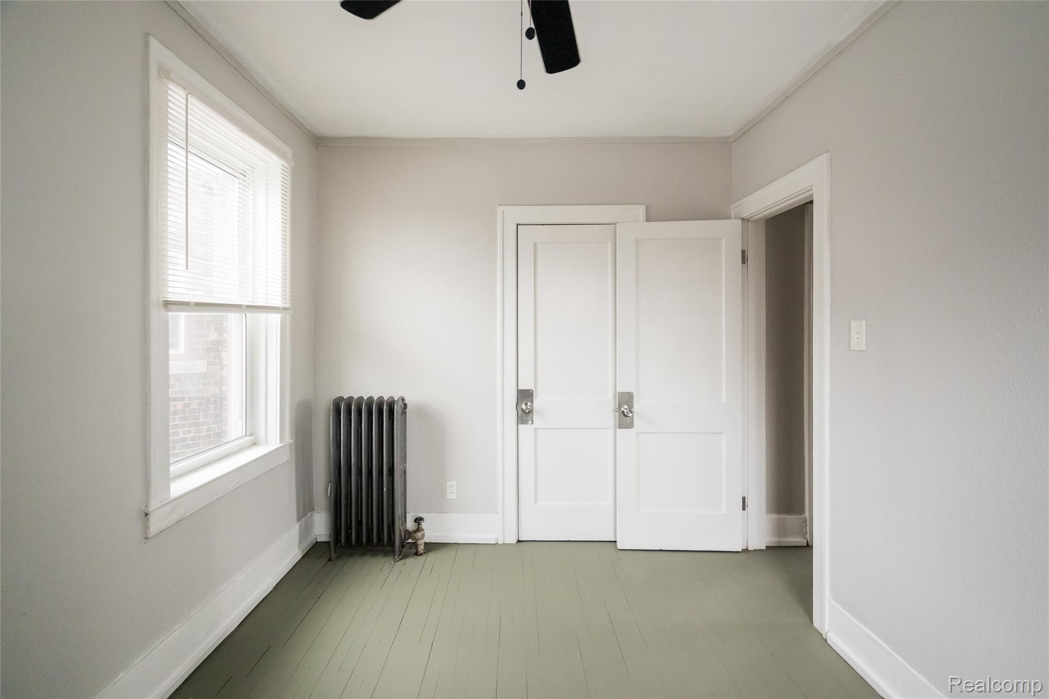 2683 Central Street Detroit, MI 48209 - Photo 10 of 10 Unfurnished bedroom with radiator heating unit, a ceiling fan, and light wood-style flooring