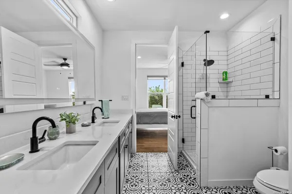 a bathroom with a double vanity sink a toilet and shower