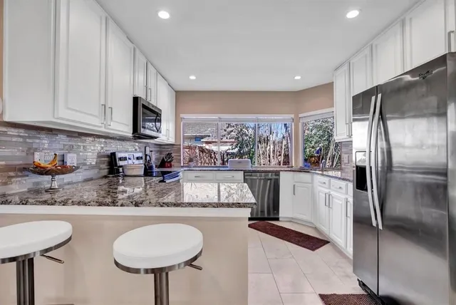 a kitchen with stainless steel appliances granite countertop a refrigerator a sink a stove a microwave and island