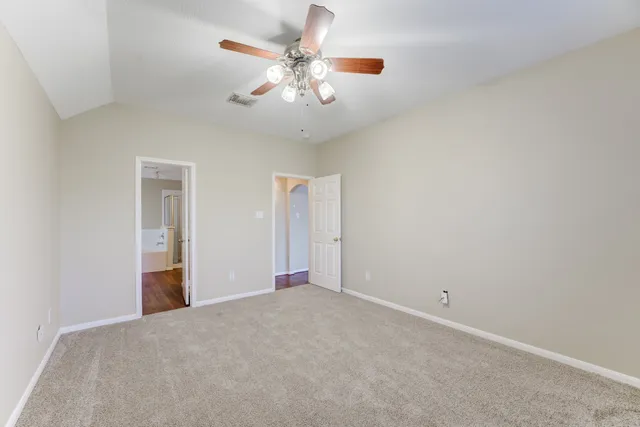 an empty room with chandelier fan and windows
