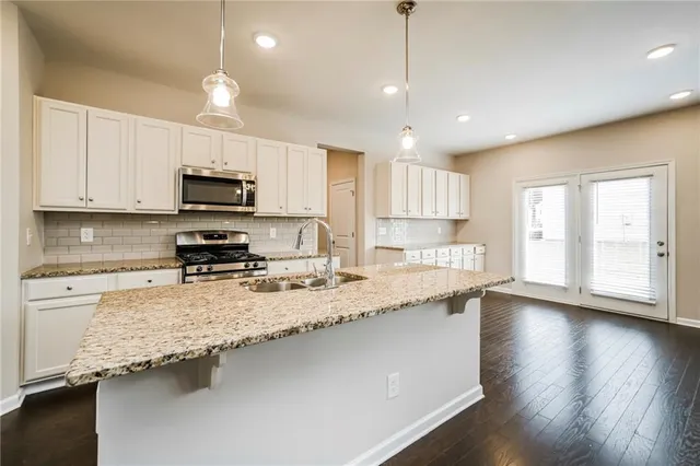 a large kitchen with granite countertop a stove a sink a center island and cabinets