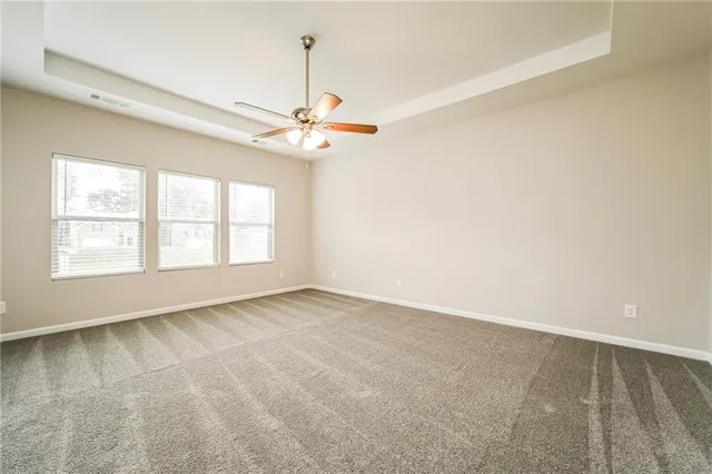 an empty room with chandelier fan and windows