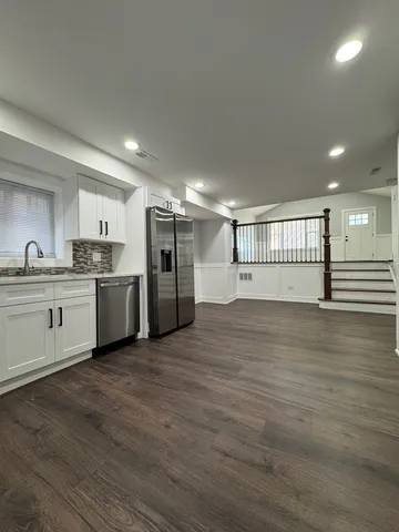 a view of a kitchen with a sink and dishwasher a refrigerator with wooden floor