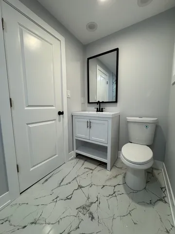 a bathroom with a toilet a sink a mirror and vanity