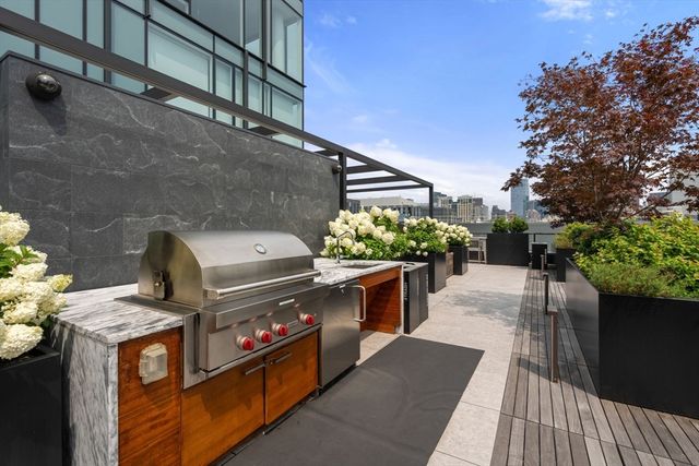 a roof deck with table and chairs and potted plants