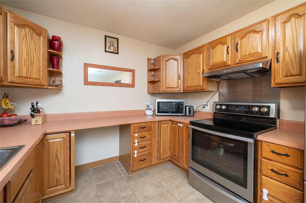151 County Road 3699 Springtown, TX 76082 - Photo 6 of 35 Kitchen featuring oak cabinetry, light-toned countertops, and tile flooring