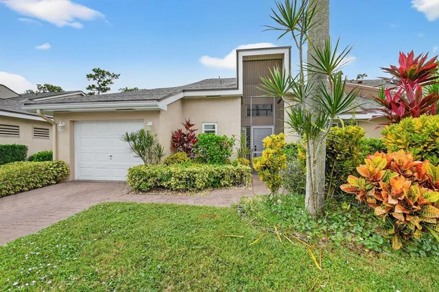a front view of a house with a yard and potted plants