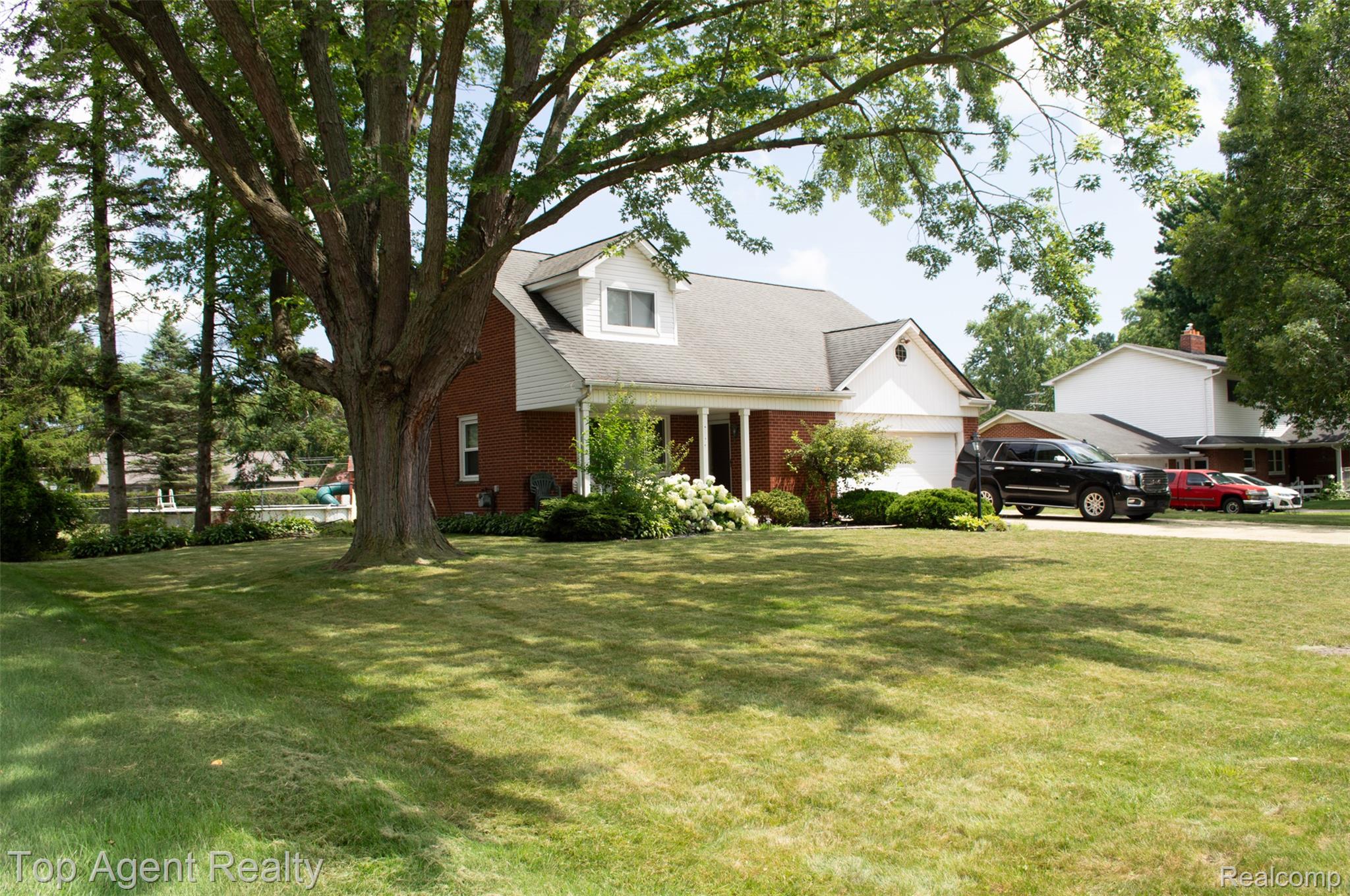 36218 Paddock Drive Clinton Township, MI 48035 - Photo 2 of 22 Brick and white siding exterior with a prominent mature tree, offering a large front lawn