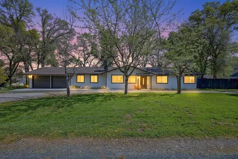 a view of a yard in front of a house with a large tree