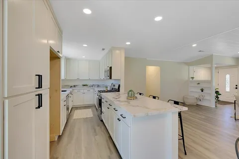 a kitchen with a sink a stove a refrigerator and white cabinets