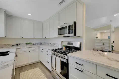 a kitchen with granite countertop a sink a stove and cabinets