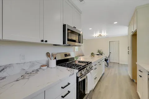 a kitchen with stainless steel appliances granite countertop a stove a sink and a white refrigerator