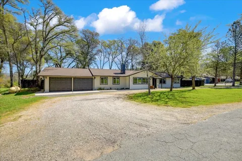 a front view of a house with a garden and trees