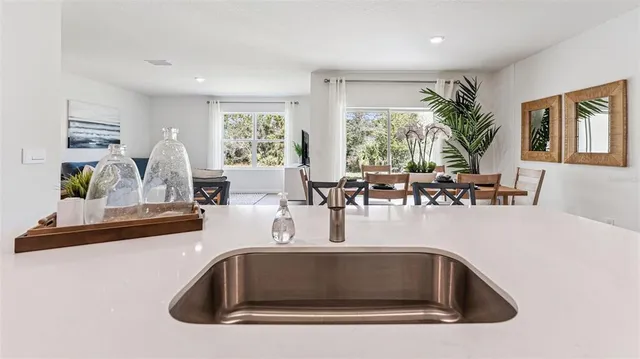 a view of kitchen with kitchen island a large window cabinets and living room view