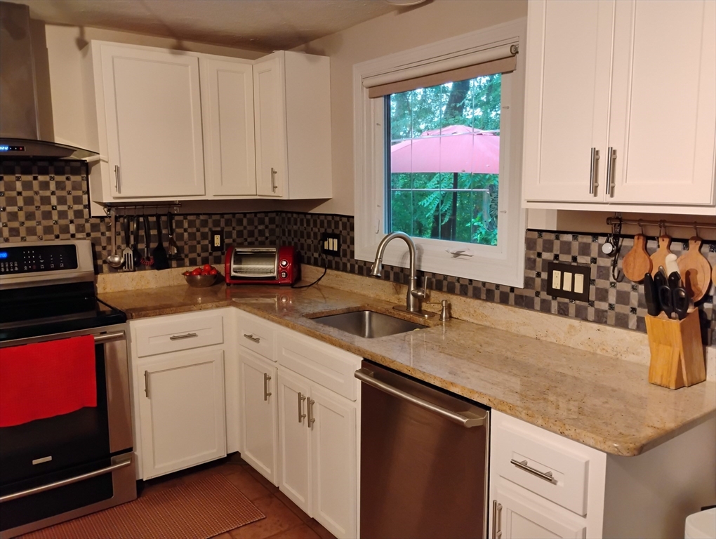 9 Packard Road Milford, MA 01757 - Photo 4 of 30 a kitchen with a stove a sink and a microwave