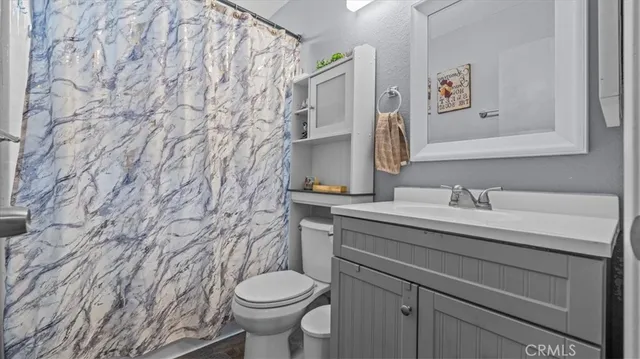a bathroom with a granite countertop sink and a toilet