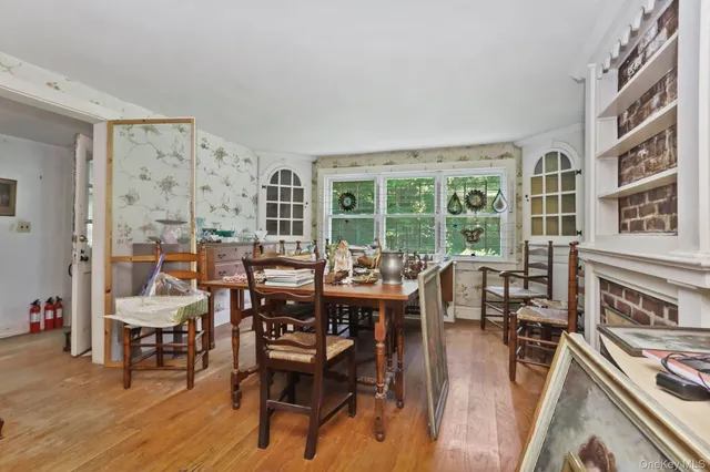 a dining room with wooden floor and large windows