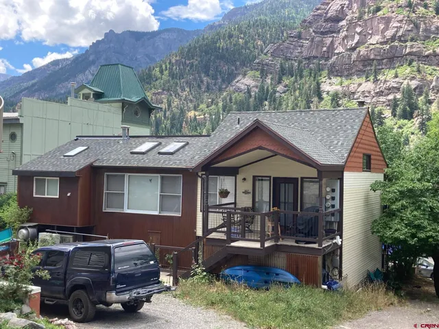a front view of a house with cars parked