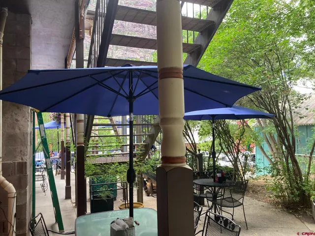 a view of a patio with table and chairs under an umbrella