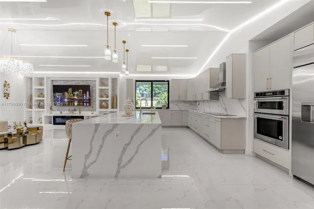 a large white kitchen with a large window and stainless steel appliances
