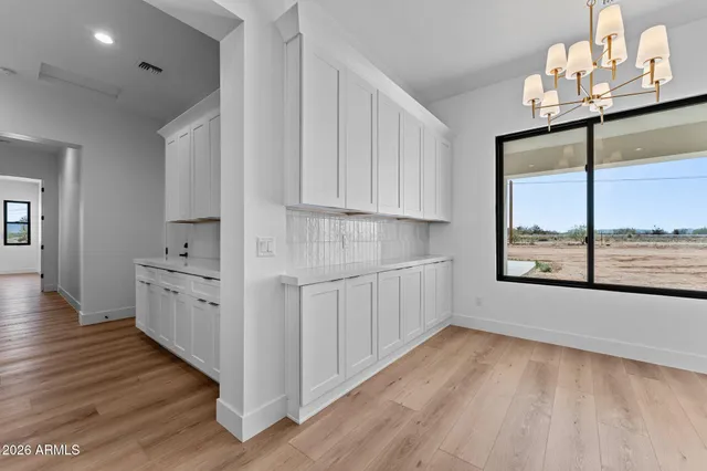 a large white kitchen with kitchen island a stove a refrigerator wooden floor and white cabinets