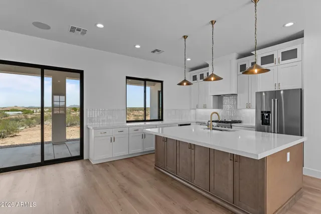 a large kitchen with stainless steel appliances granite countertop a large counter top a stove and a wooden floors