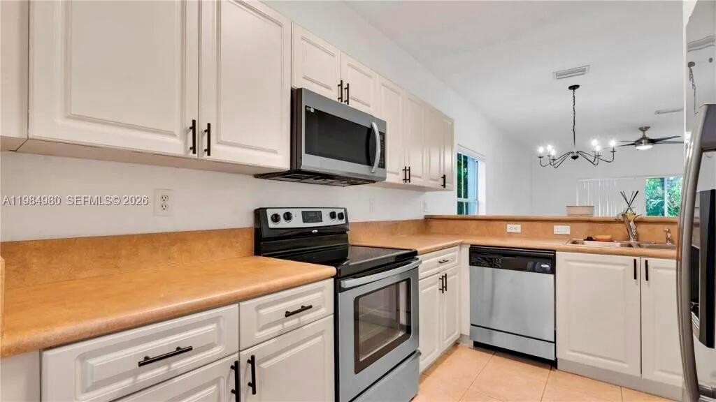 4921 Southwest 140th Terrace, Unit 1 Miramar, FL 33027 - Photo 6 of 16 a kitchen with stainless steel appliances white cabinets and a stove a oven with wooden floor