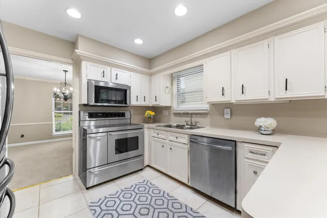 a kitchen with granite countertop white cabinets and stainless steel appliances