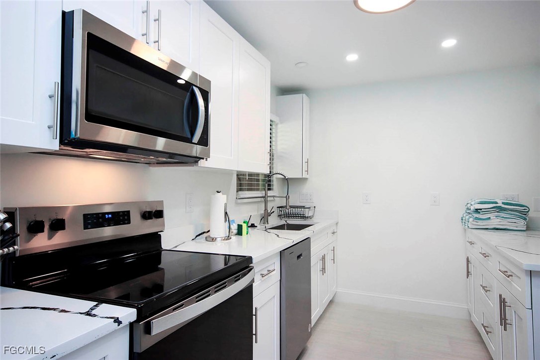 5117 Sea Bell Road, Unit A102 Sanibel, FL 33957 - Photo 12 of 21 a kitchen with stainless steel appliances a stove a microwave a sink and cabinets