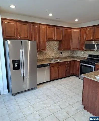 a kitchen with stainless steel appliances granite countertop a stove top oven a sink and a refrigerator