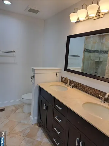 a bathroom with a granite countertop toilet sink and mirror