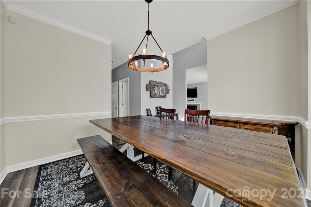 3307 Creek Trail Road Indian Trail, NC 28079 - Photo 6 of 43 a dining room with wooden floor a chandelier a wooden table and chairs