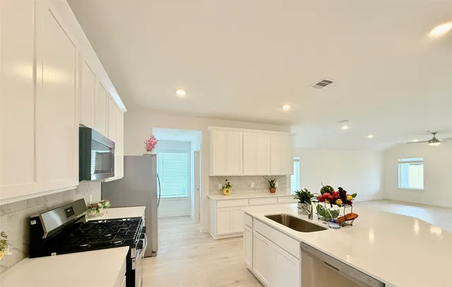 a kitchen that has a sink and a stove with wooden floor