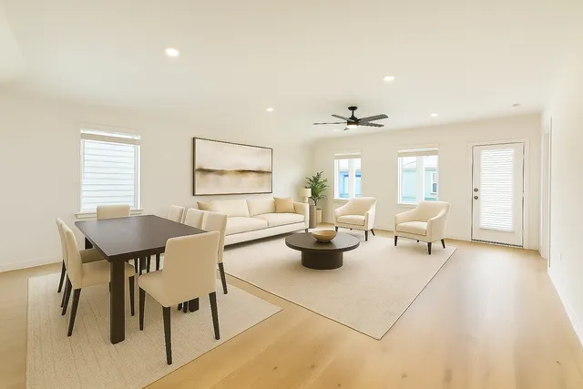a living room with lots of white furniture and a potted plant
