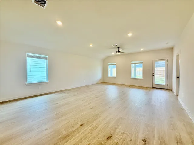 an empty room with wooden floor and windows