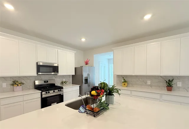 a kitchen with stainless steel appliances kitchen island granite countertop a stove a sink dishwasher and a refrigerator with wooden floor