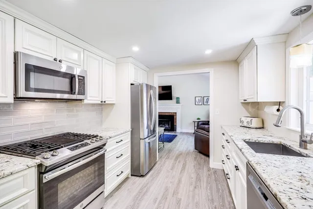 a kitchen with stainless steel appliances kitchen island granite countertop a stove a sink dishwasher a refrigerator and a microwave oven with wooden floor