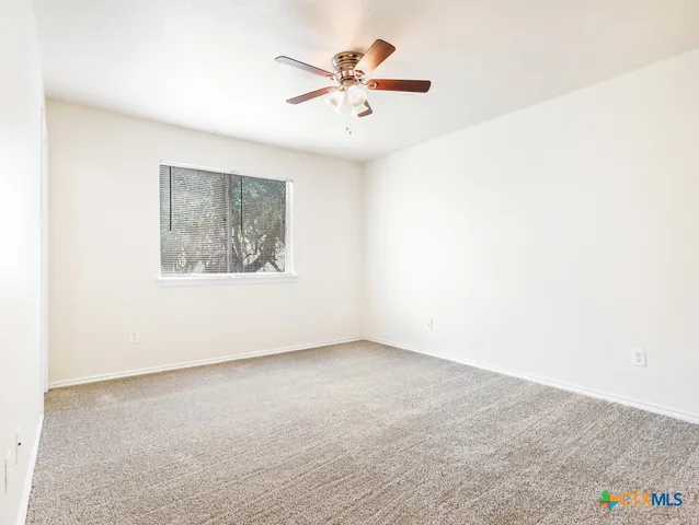 an empty room with a ceiling fan and a window