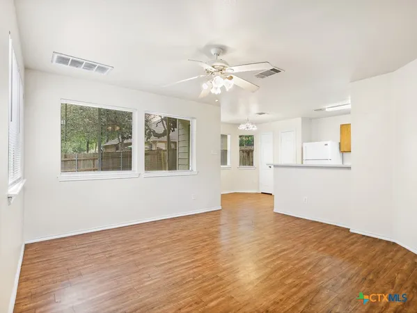 a view of an empty room with a window and wooden floor